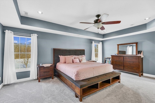 carpeted bedroom with ceiling fan and a tray ceiling