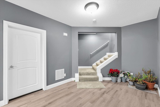 foyer entrance featuring a textured ceiling and light wood-type flooring