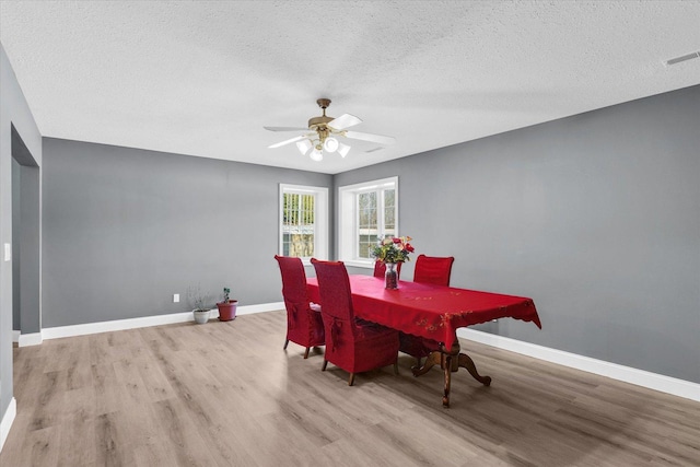 dining space with light hardwood / wood-style floors, a textured ceiling, and ceiling fan