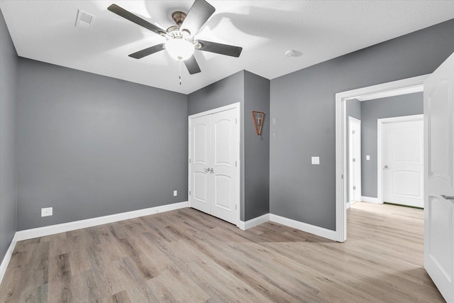 unfurnished bedroom with ceiling fan, a textured ceiling, light hardwood / wood-style flooring, and a closet