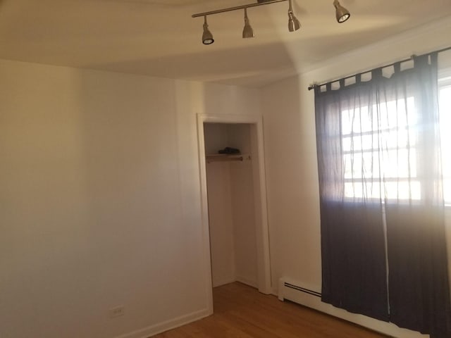 unfurnished room with hardwood / wood-style flooring and a baseboard radiator