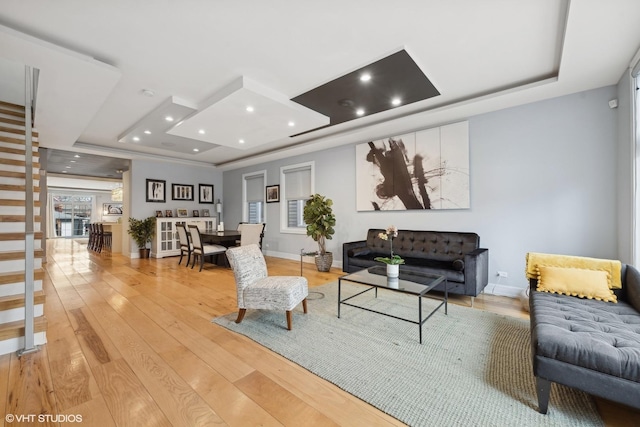 living room with light hardwood / wood-style floors and a tray ceiling