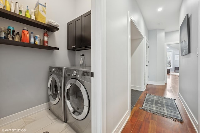 clothes washing area with cabinets and washing machine and dryer