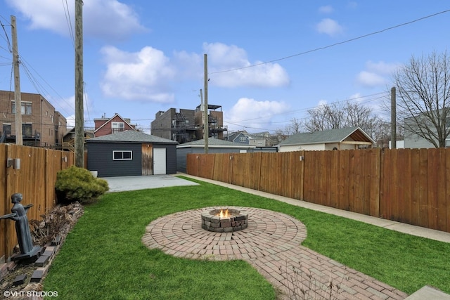 view of yard featuring a garage, an outbuilding, a patio area, and a fire pit