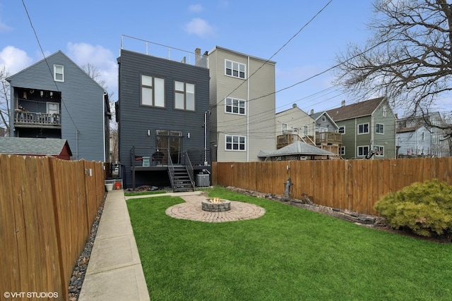 rear view of property featuring a yard, a patio area, and a fire pit