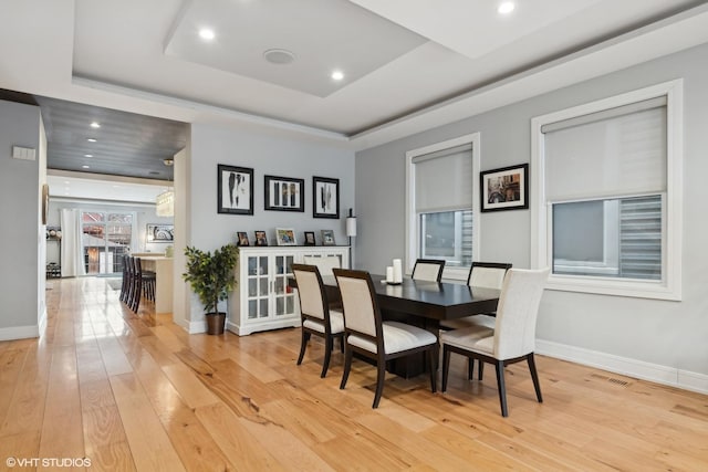 dining area featuring a raised ceiling and light hardwood / wood-style floors