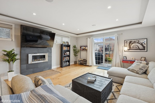 living room featuring a raised ceiling, hardwood / wood-style flooring, and a fireplace