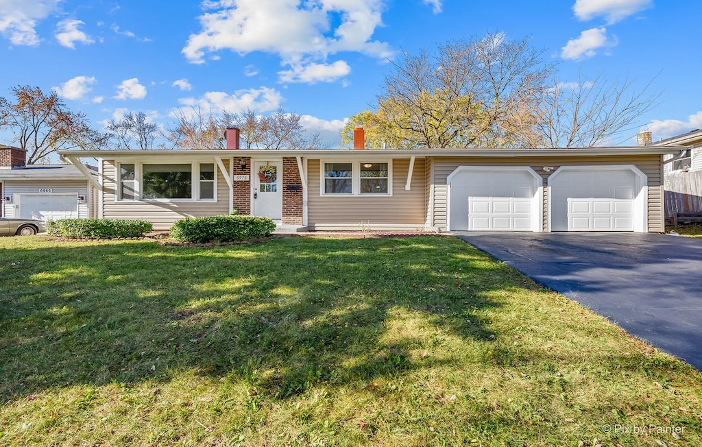 single story home featuring a garage and a front lawn