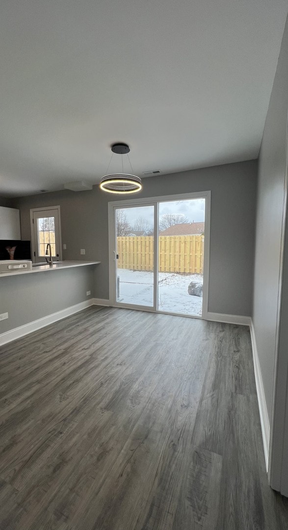 unfurnished living room featuring a wealth of natural light, dark wood-type flooring, and sink