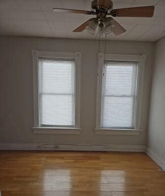 unfurnished room with baseboards, a healthy amount of sunlight, ceiling fan, and light wood finished floors