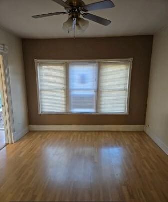 spare room featuring ceiling fan, baseboards, and wood finished floors