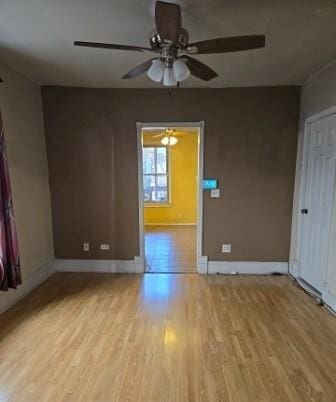 spare room featuring a ceiling fan, baseboards, and wood finished floors