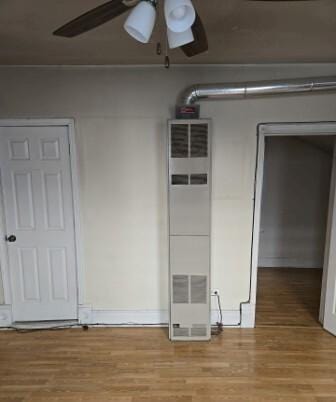 empty room with a heating unit, ceiling fan, and light wood finished floors