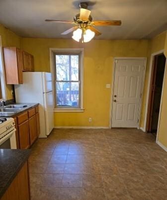 kitchen featuring baseboards, ceiling fan, a sink, dark countertops, and brown cabinets