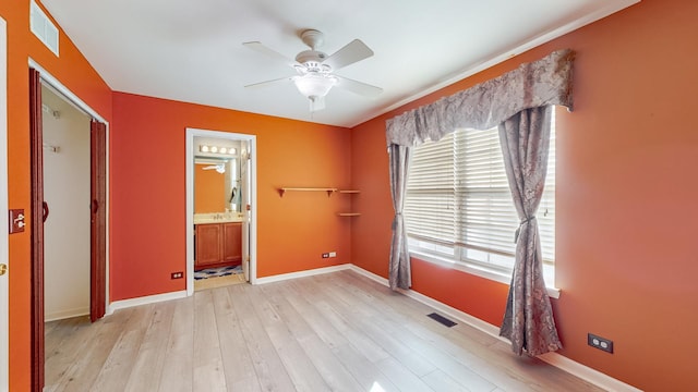 unfurnished bedroom with multiple windows, connected bathroom, ceiling fan, and light hardwood / wood-style flooring