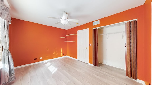 unfurnished bedroom with ceiling fan, light wood-type flooring, and a closet