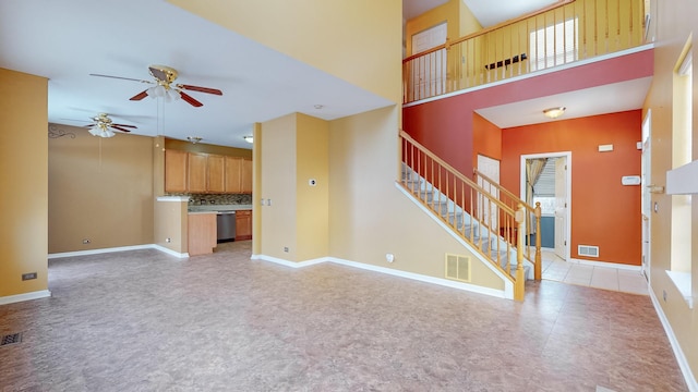 unfurnished living room with ceiling fan and a high ceiling