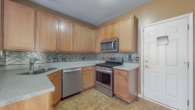 kitchen with light stone counters, appliances with stainless steel finishes, sink, and decorative backsplash