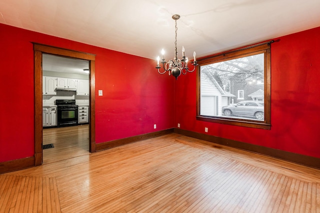 unfurnished dining area featuring a notable chandelier and light hardwood / wood-style flooring