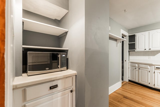 kitchen featuring white cabinets, light wood-type flooring, and tasteful backsplash