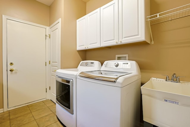 washroom with cabinets, washing machine and clothes dryer, sink, and light tile patterned floors