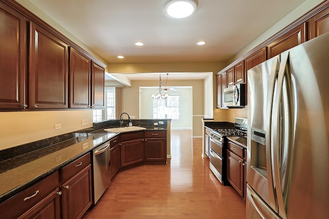 kitchen featuring decorative light fixtures, sink, light wood-type flooring, stainless steel appliances, and an inviting chandelier