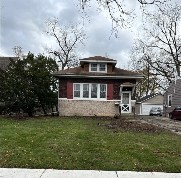 view of front of property featuring a garage, an outbuilding, and a front lawn