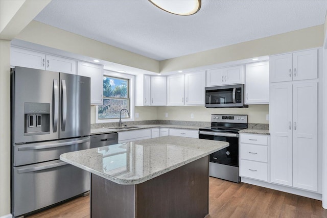 kitchen with sink, white cabinetry, light stone counters, a kitchen island, and stainless steel appliances