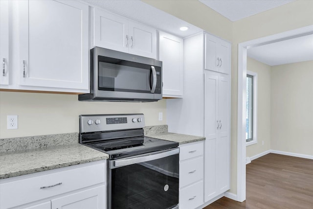 kitchen featuring dark hardwood / wood-style flooring, light stone countertops, white cabinets, and appliances with stainless steel finishes