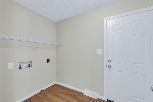 laundry area featuring hookup for an electric dryer, hookup for a washing machine, hardwood / wood-style floors, and a textured ceiling