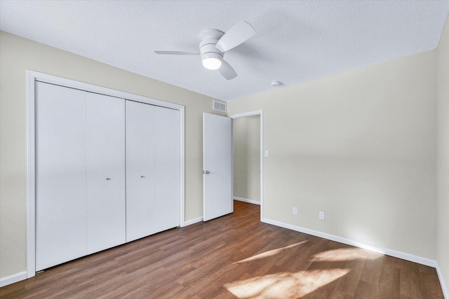 unfurnished bedroom with ceiling fan, wood-type flooring, a closet, and a textured ceiling