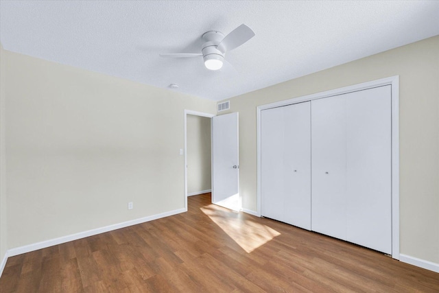 unfurnished bedroom with hardwood / wood-style floors, a textured ceiling, ceiling fan, and a closet