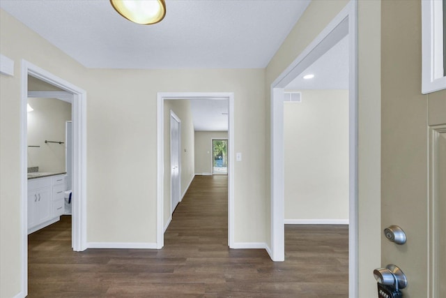 hallway with dark hardwood / wood-style flooring and a textured ceiling