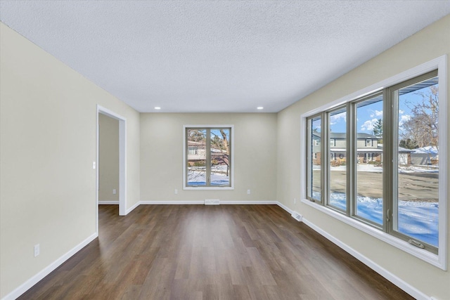 spare room with dark hardwood / wood-style flooring and a textured ceiling