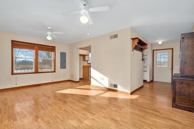 unfurnished living room with electric panel, a wealth of natural light, ceiling fan, and light hardwood / wood-style floors