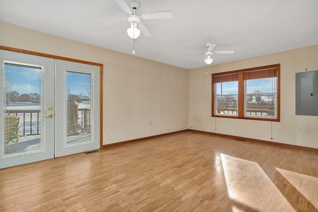 spare room with electric panel, ceiling fan, french doors, and light wood-type flooring