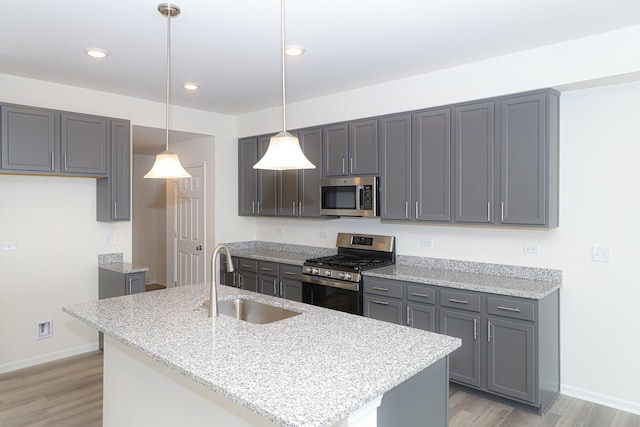 kitchen featuring pendant lighting, sink, appliances with stainless steel finishes, and an island with sink