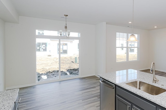 kitchen featuring light stone countertops, stainless steel dishwasher, sink, wood-type flooring, and decorative light fixtures