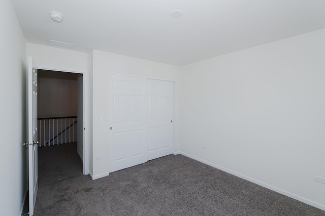 unfurnished bedroom featuring dark colored carpet and a closet