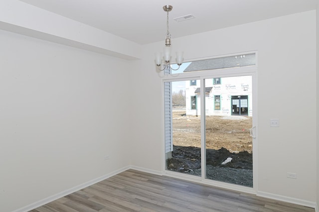 unfurnished dining area featuring wood-type flooring and a notable chandelier