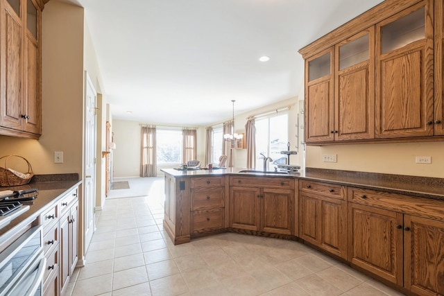 kitchen featuring kitchen peninsula, decorative light fixtures, a notable chandelier, light tile patterned flooring, and sink