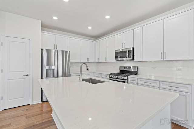 kitchen featuring white cabinetry, a kitchen island with sink, sink, and appliances with stainless steel finishes