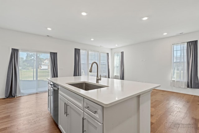 kitchen with dishwasher, a center island with sink, light hardwood / wood-style flooring, and sink