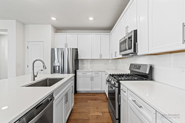 kitchen with white cabinetry, sink, stainless steel appliances, dark hardwood / wood-style flooring, and decorative backsplash