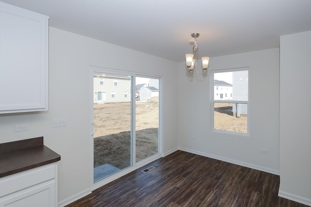 unfurnished dining area featuring dark hardwood / wood-style floors and an inviting chandelier