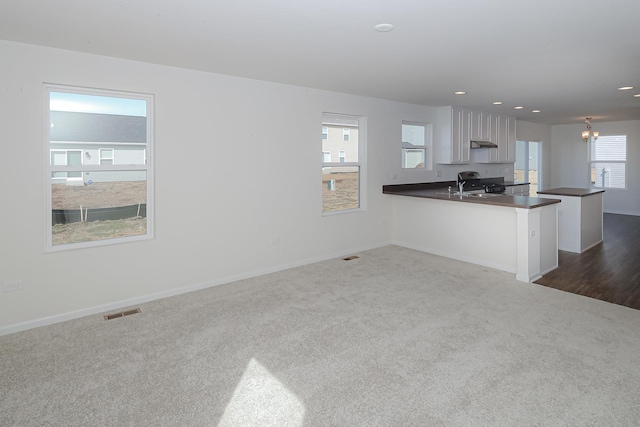 unfurnished living room with dark carpet and a chandelier