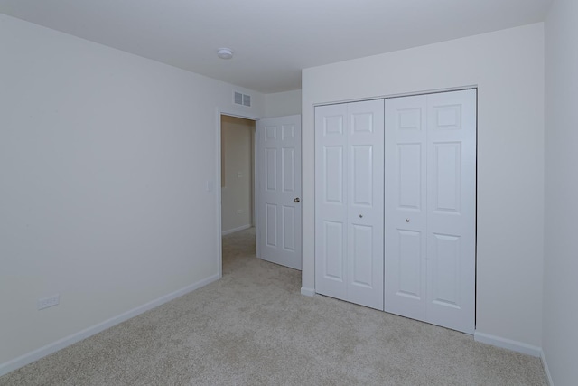 unfurnished bedroom featuring a closet and light colored carpet