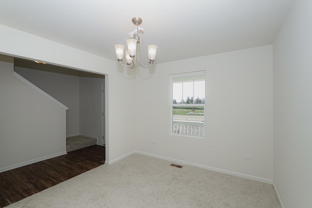 unfurnished room with dark colored carpet and an inviting chandelier