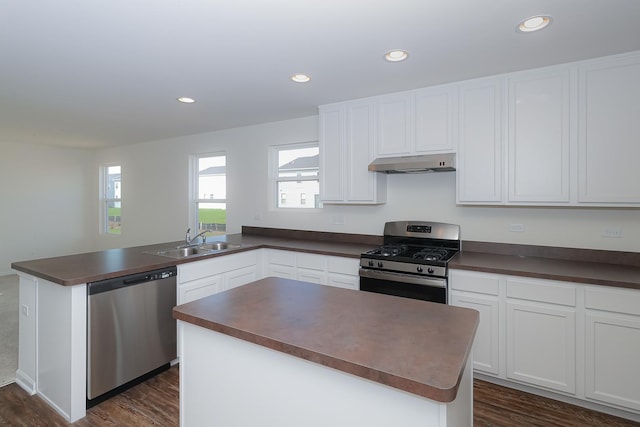 kitchen with dark hardwood / wood-style flooring, stainless steel appliances, sink, white cabinetry, and a kitchen island