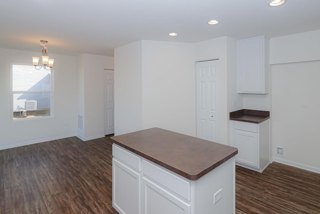 kitchen with dark hardwood / wood-style floors, a center island, white cabinetry, and an inviting chandelier